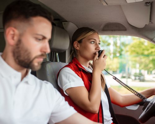 Paramedic answers an emergency call from an ambulance. Young woman answering a call in an ambulance. She's with her colleague.